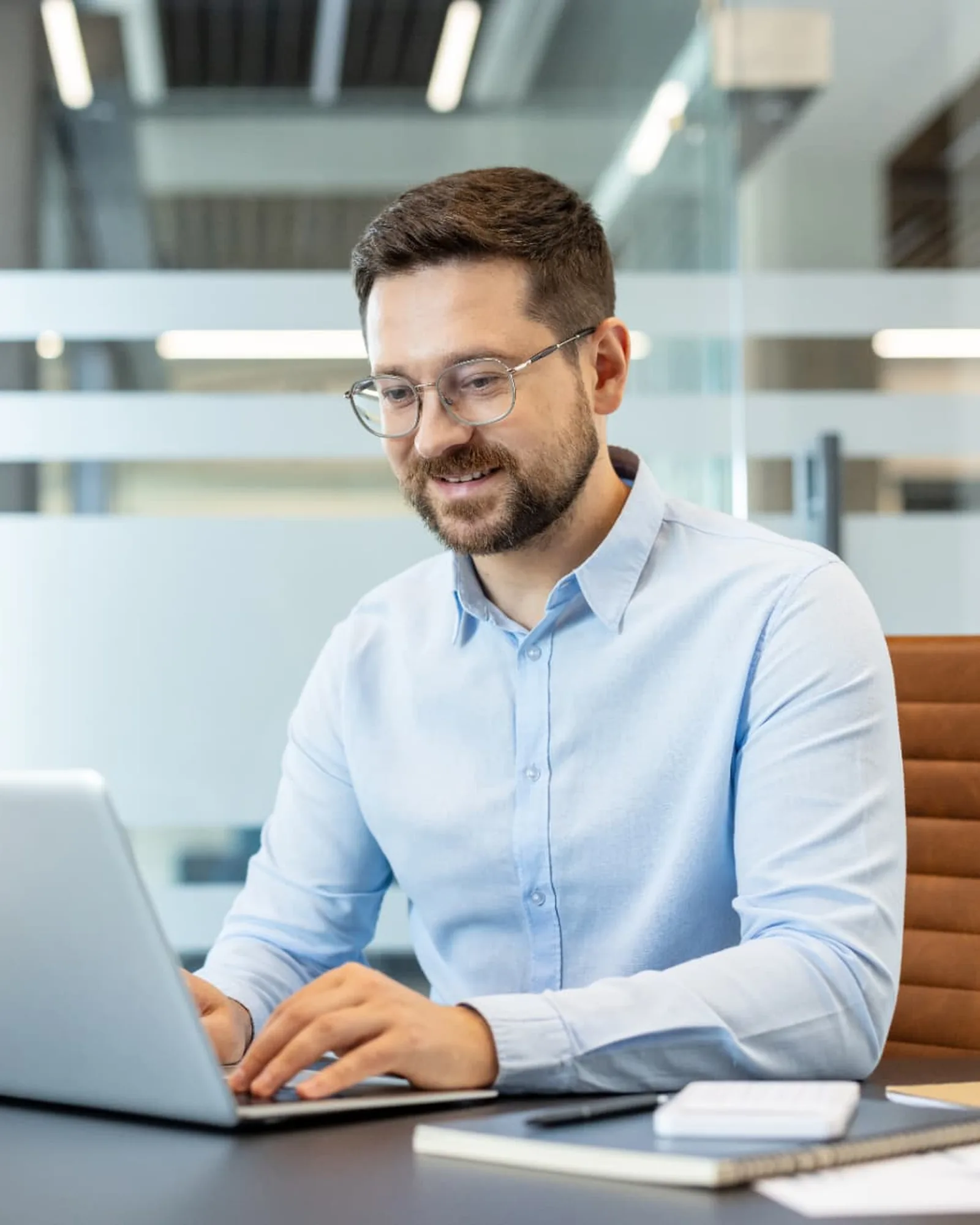 Lyst kontor med dagslys, hvor en medarbejder arbejder koncentreret ved sin bærbare computer